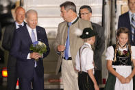 President Joe Biden, left, holds a bouquet that was given to him by children as he is accompanied by Bavarian Prime Minister Markus Soeder after arriving at Franz-Josef-Strauss Airport near Munich, Germany Saturday, June 25, 2022, ahead of the G7 summit. The G7 Summit will take place at Castle Elmau near Garmisch-Partenkirchen from June 26 through June 28, 2022. (AP Photo/Markus Schreiber)