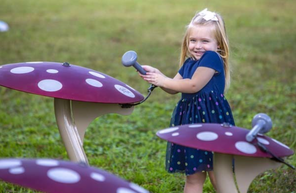 A young girl plays musical playground equipment made by Freenotes Harmony Park.