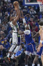 Milwaukee Bucks forward Giannis Antetokounmpo, left, scores against Golden State Warriors center Kevon Looney during the first half of an NBA basketball game in San Francisco, Saturday, March 12, 2022. (AP Photo/Jeff Chiu)