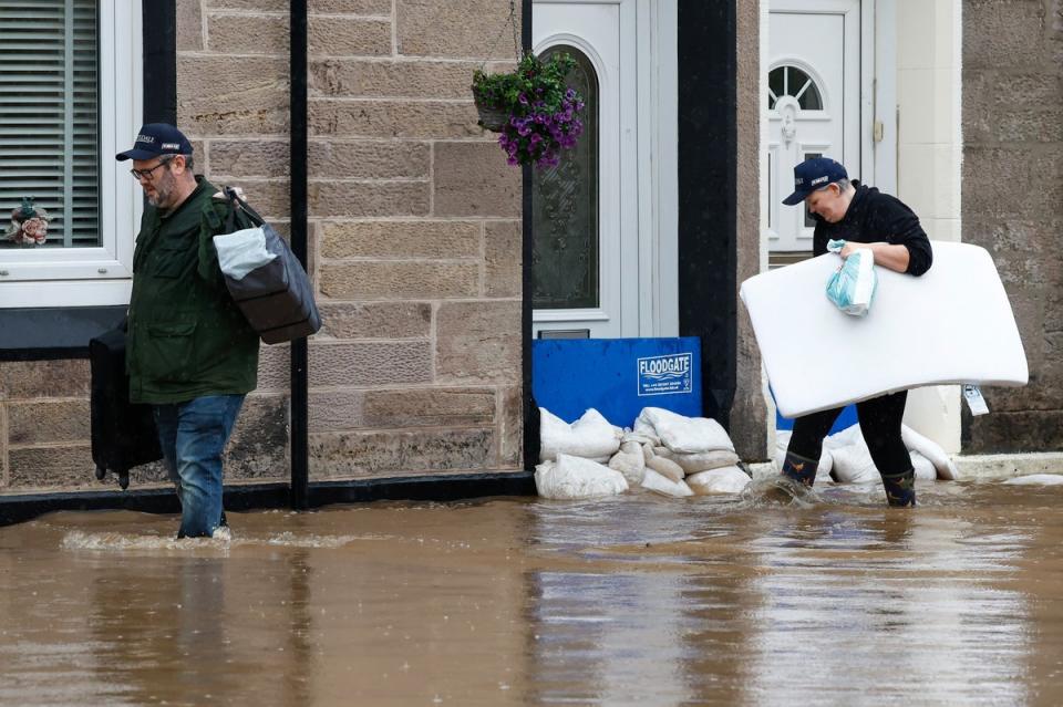 Members of the public struggle with flooding as torrential rain continues in Dumbarton, Scotland, on Saturday (Getty Images)