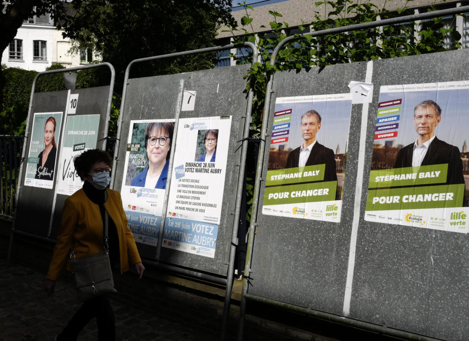 A woman walks past posters advertising the upcoming local election candidates in Lille Sunday, June 28, 2020 in Lille, northern France. France is holding the second round of municipal elections in 5,000 towns and cities Sunday that were postponed due to the country's coronavirus outbreak.(AP Photo/Michel Spingler)