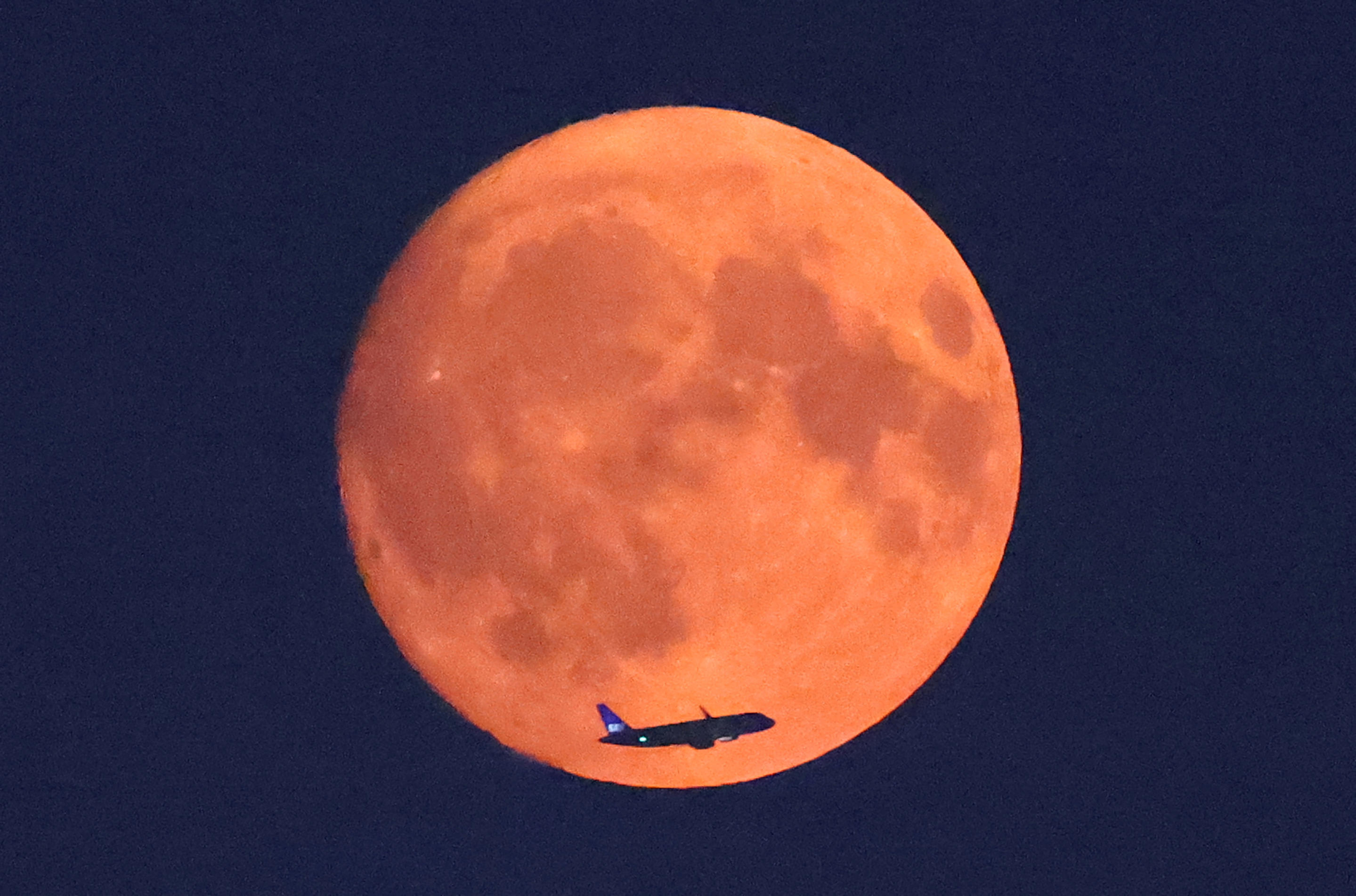 An aircraft passes in front of the moon in London on Monday. 