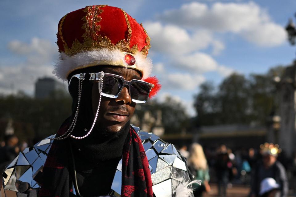 A royal fan wearing a crown and a shattered-mirror suit mingles with tourists outside Buckingham Palace (AFP/Getty)