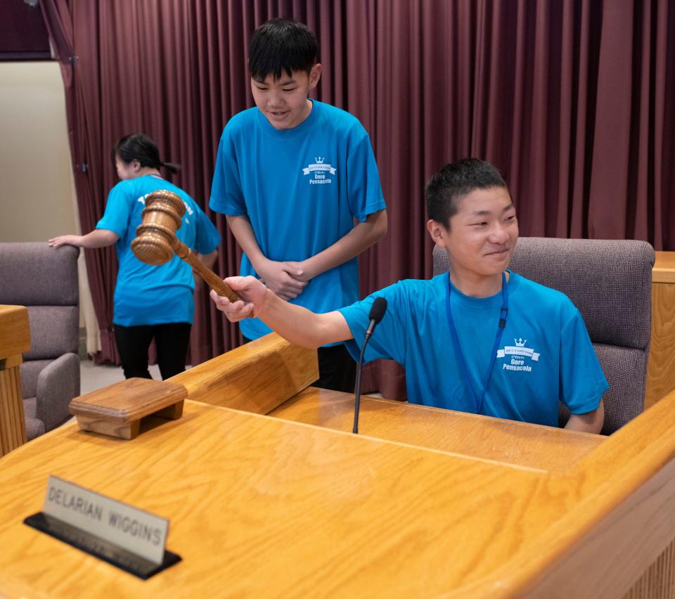 Japanese exchange students take turns with the gavel while sitting on the Pensacola City Council dais during a visit to City Hall on Wednesday, March 29, 2023.