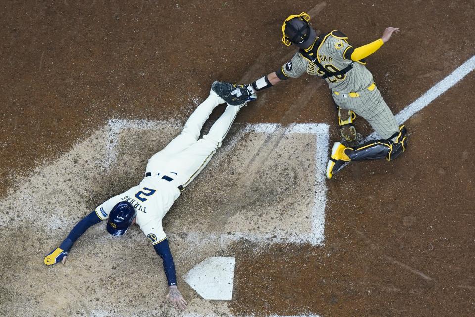 Milwaukee Brewers' Brice Turang slides safely past San Diego Padres catcher Kyle Higashioka during the eighth inning of a baseball game Wednesday, April 17, 2024, in Milwaukee. (AP Photo/Morry Gash)