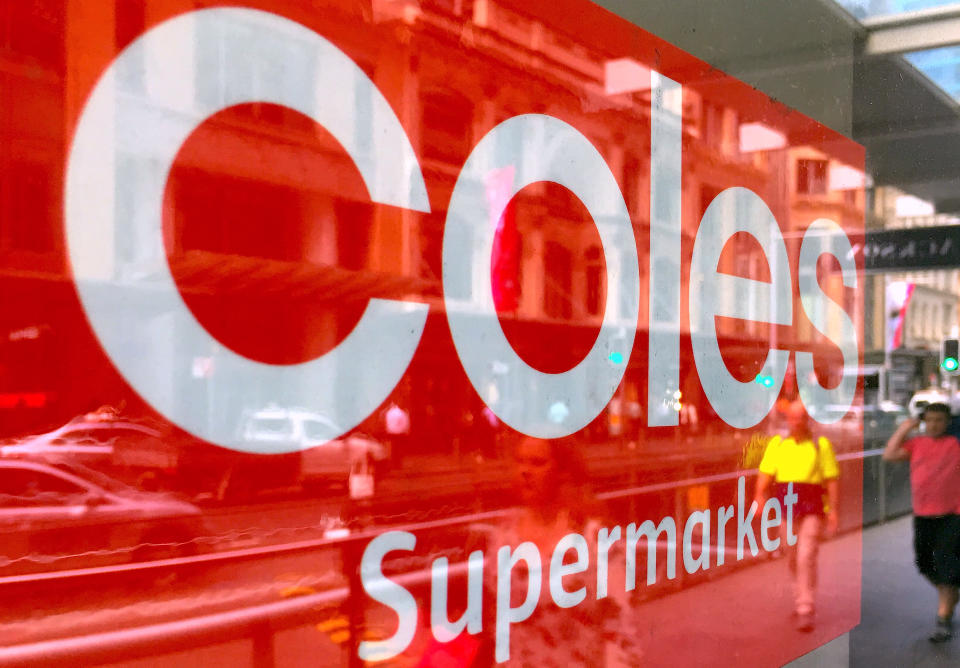 Coles logo in a window, people walking past in reflection. Source: Reuters/Steven Saphore