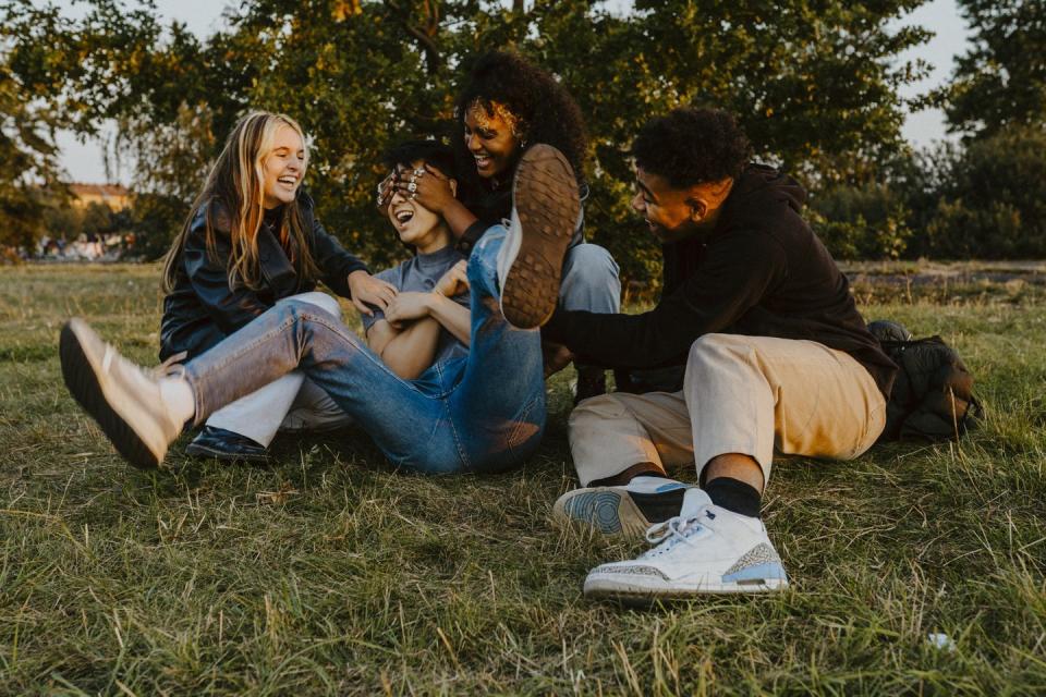 cheerful male and female friends having fun while playing in park during sunset