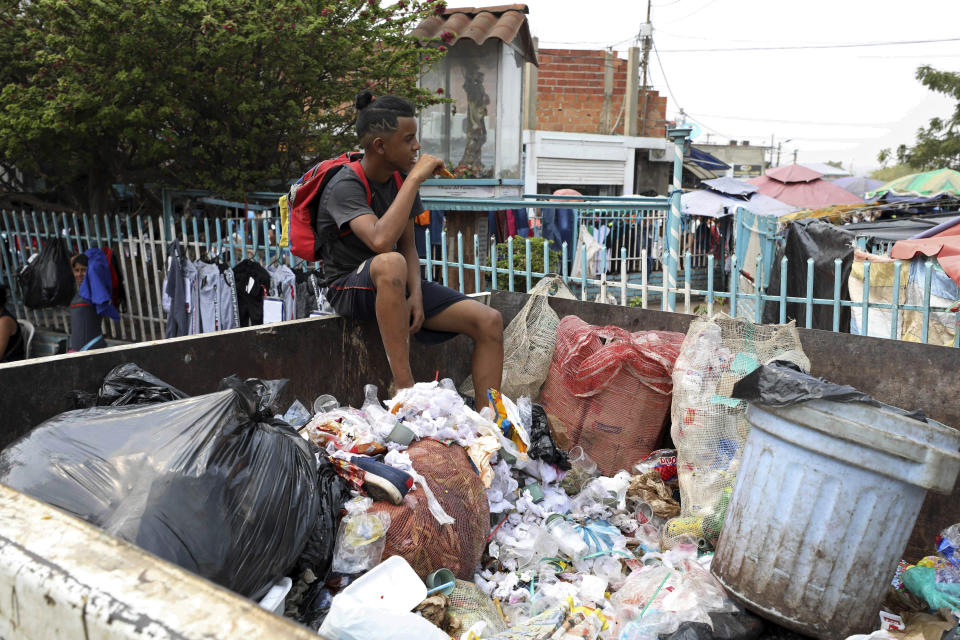 A Venezuelan youth pauses from searching through a trash bin in La Parada, on the outskirts of Cucuta, Colombia, on the border with Venezuela, Monday, Feb. 4, 2019. Venezuelan opposition leader Juan Guaido is moving ahead with plans to try to bring in humanitarian aid through the Colombian border city of Cucuta, where the U.S. government will transport and store food and medical supplies destined for Venezuela. (AP Photo/Fernando Vergara)