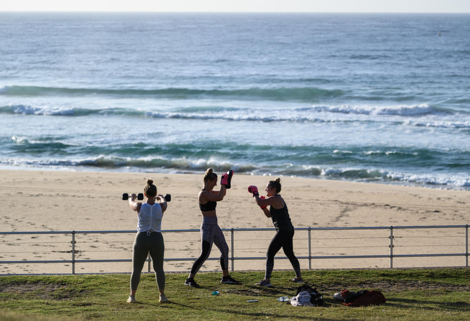 Three people exercise at Bondi Beach. This means exercise bootcamps will have to be limited to one-on-one sessions.