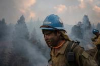 Firefighter walks past smoke rising from Brattain Fire in Fremont National Forest in Paisley, Oregon