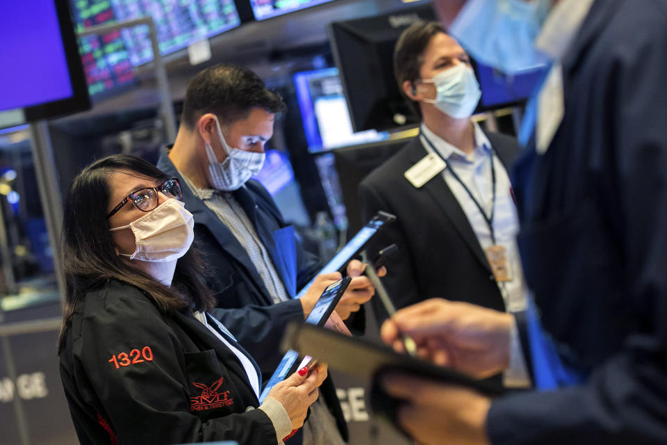In this photo provided by the New York Stock Exchange, Phyllis Arena Woods, left, works with other traders on the floor, Friday, Feb 26, 2021. Stocks wobbled between small gains and losses on Wall Street Friday as rising technology stocks offset a slide in banks and energy companies. (Courtney Crow/New York Stock Exchange via AP)
