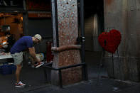 A man ties his shoe next to a wreath at the entrance to La Boqueria market, near the area where a van crashed into pedestrians at Las Ramblas in Barcelona, Spain August 21, 2017. REUTERS/Susana Vera