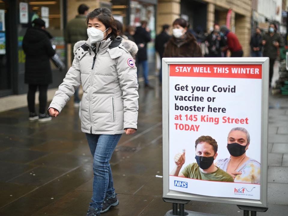 A woman walks past signage outside a pop-up Covid vaccination centre in Hammersmith, London (AFP via Getty Images)