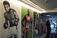 Photographs of Muhammad Ali, left, Carl Lewis, center, and Sergei Bubka are displayed during an exhibition press day, Wednesday, March 27, 2024 in Paris. Ahead of this summer's Paris Olympics, an exhibit in the French capital shows how the Games have been a "mirror of society" since the beginning of the 20th century. (AP Photo/Laurent Cipriani)