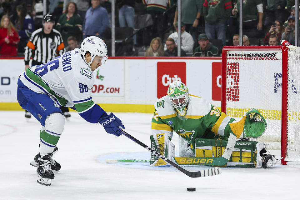 Vancouver Canucks left wing Andrei Kuzmenko (96) attempts a shot on Minnesota Wild goaltender Filip Gustavsson (32) during the shootout in an NHL hockey game Saturday, Dec. 16, 2023, in St Paul, Minn. (AP Photo/Matt Krohn)