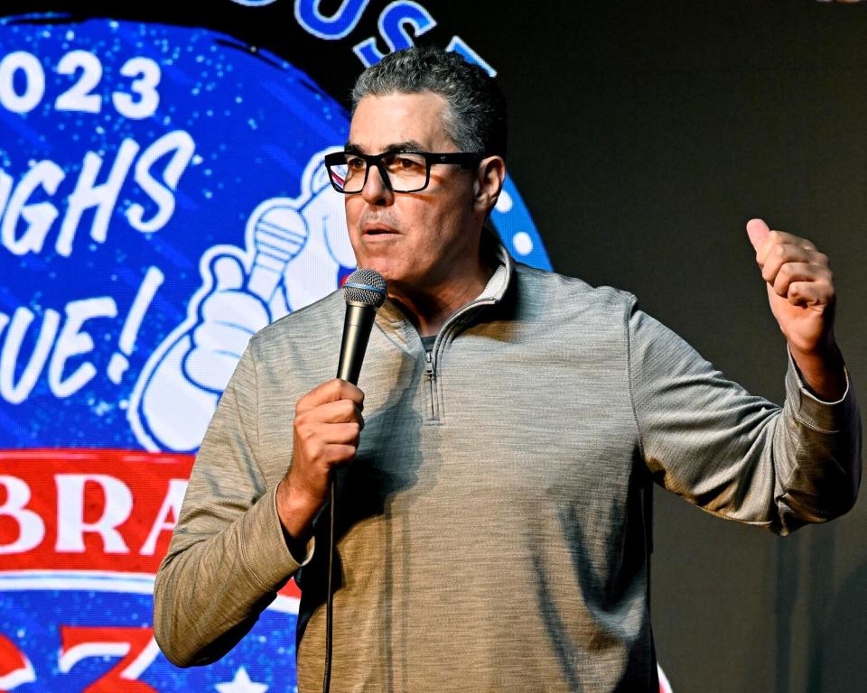 Man standing on stage with glasses and a microphone