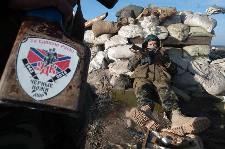 A pro-Russian rebel holds a rifle with the emblem of the unit "Black knife" that reads " For united Rus" as another rests at their position near the eastern Ukrainian vallage of Frunze, Lugansk region, on March 24, 2015