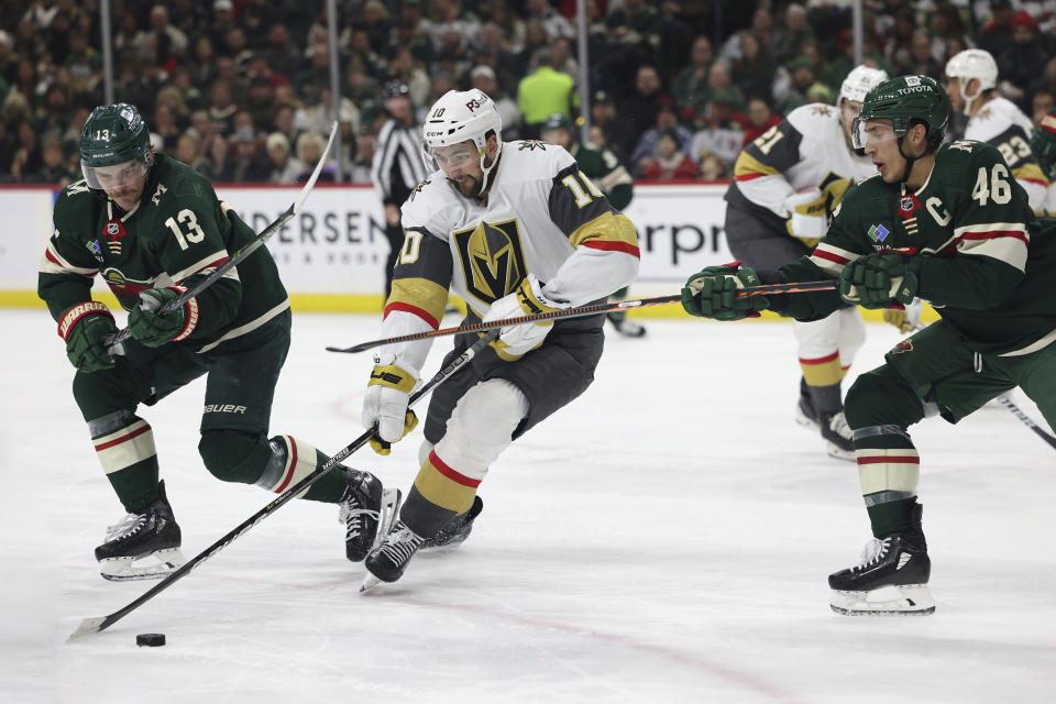 Vegas Golden Knights center Nicolas Roy (10) handles the puck against Minnesota Wild center Sam Steel (13) and defenseman Jared Spurgeon (46) during the second period of an NHL hockey game Monday, April 3, 2023, in St. Paul, Minn. (AP Photo/Stacy Bengs)