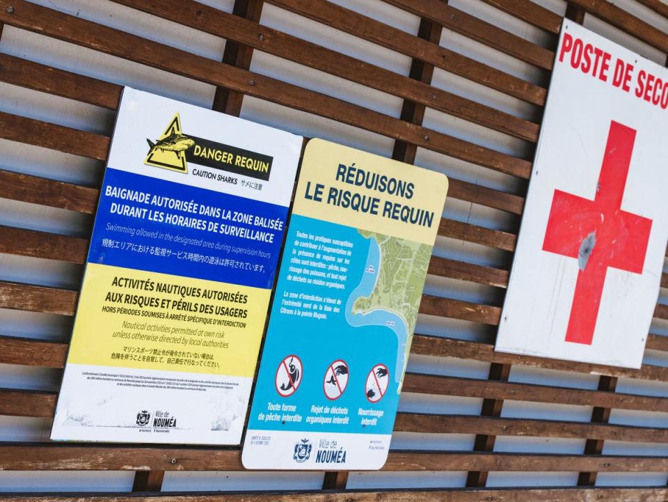 Signage at a lifeguard station warns of risk of shark attacks and indicates the presence of a perimeter of supervised swimming area protected by a newly-installed maritime net barrier at a beach along the Baie des Citrons bay in Noumea, New Caledonia, 6 December 2023 (AFP via Getty Images)