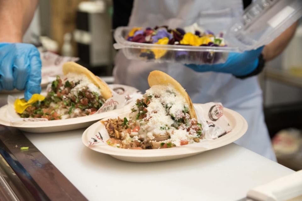 Andy's Latin Food co-owner Andres Villalobos places a nasturtium blossom on one of his signature meals, Andy's Fave Arepa. The dish features pulled pork, queso fresco, pico de gallo, Venezuelan cheese and green sauce.