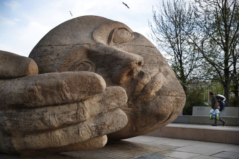 A homeless, at right, walks by "Ecoute", a sculpture by French artist Henri de Miller in the Nelson Mandela Garden in Paris, April 2020