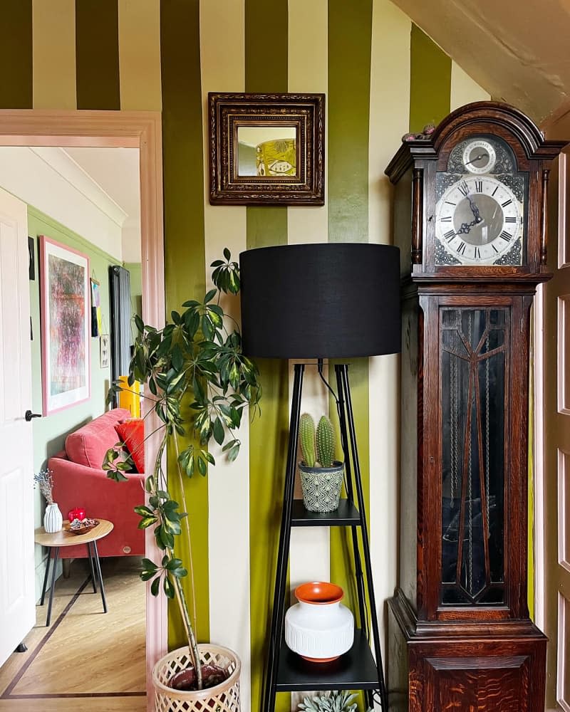 Green and white striped painted wall in entry of home with grandfather clock.