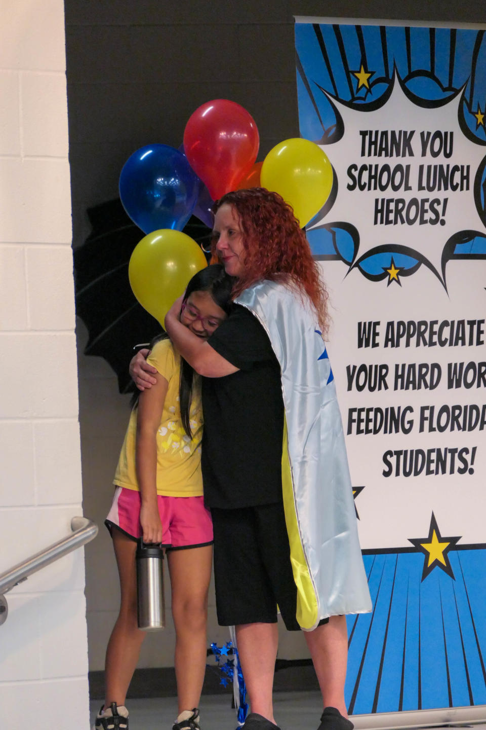 Angela Kelly, one of five recipients of the 2024 Florida School Lunch Heroes award, hugs Hailey Do, 9. The surprise award ceremony was held in the cafeteria at Lawton Chiles Elementary in Gainesville, Fla. on May 6, 2024.