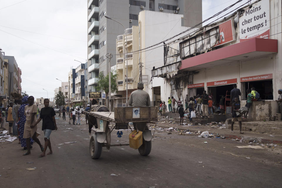 People stand at the entrance of a destroyed supermarket in Dakar, Senegal, Saturday, June 3, 2023. Senegal's government says at least nine people have been killed in violent clashes between police and supporters of opposition leader Ousmane Sonko, with authorities issuing a blanket ban on the use of several social media platforms in the aftermath of the violence. (AP Photo/Leo Correa)