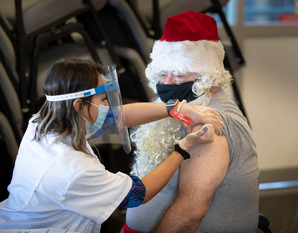 Florida Presbyterian Homes CEO Joe Xanthopoulos, dressed as Santa, receives a Pfizer Covid-19 vaccination from Walgreens Pharmacist Ericka Gutierrez at the Florida Presbyterian Homes in Lakeland, Florida, on Tuesday, Dec. 22.