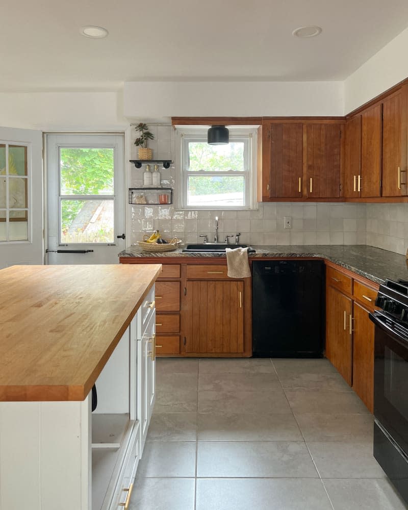 Wood cabinets with brass handles in newly renovated kitchen.