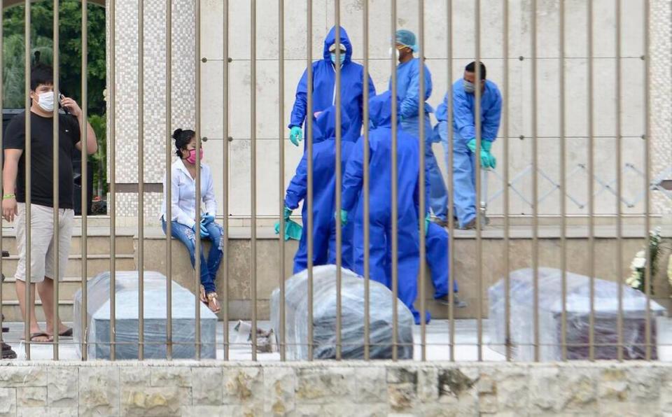 Cemetery workers in Guayaquil, Ecuador, wait to burry people who died from COVID-19 in April 2020. Their coffins were wrapped in plastic.