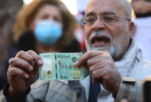 A man displays a banknote of 100,000 Lebanese pounds during a protest against the collapse of the national currency in front of the Central Bank 