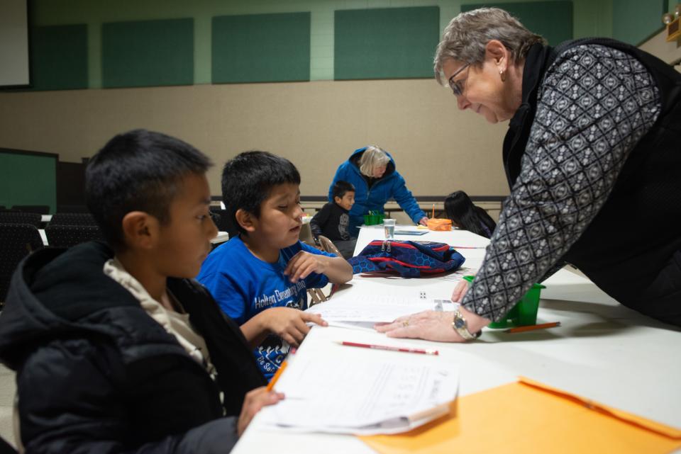 Billie McClure roams the tables at Evangel Church's Family Life Center in Holton helping immigrant children from Guatemala with their schoolwork Thursday afternoon.