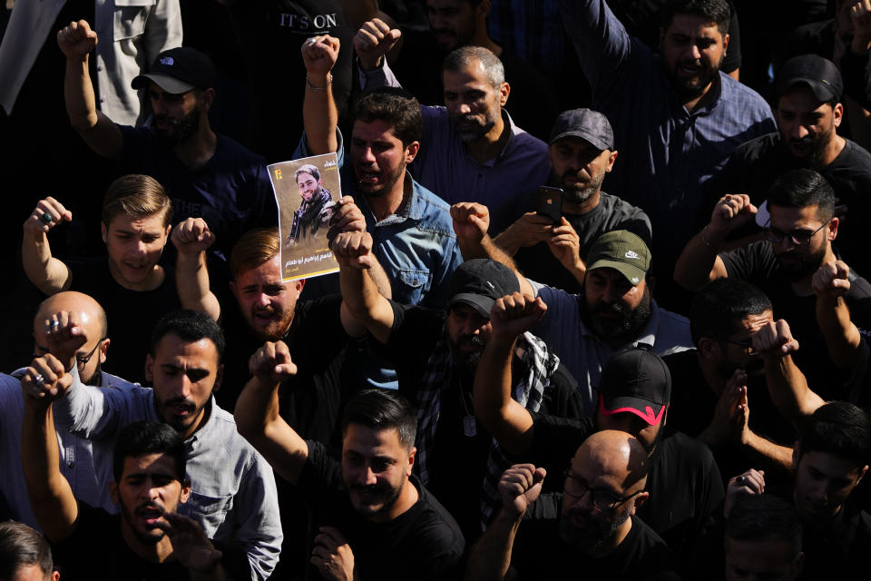 People shout slogans as they attend the funeral procession of Hezbollah fighter, Qassim Ibrahim Abu-Taam, seen in the picture, who was killed by Israeli shelling, during his funeral procession in the southern Beirut suburb of Dahiyeh, Lebanon, Monday, Nov. 6, 2023. (AP Photo/Hassan Ammar)