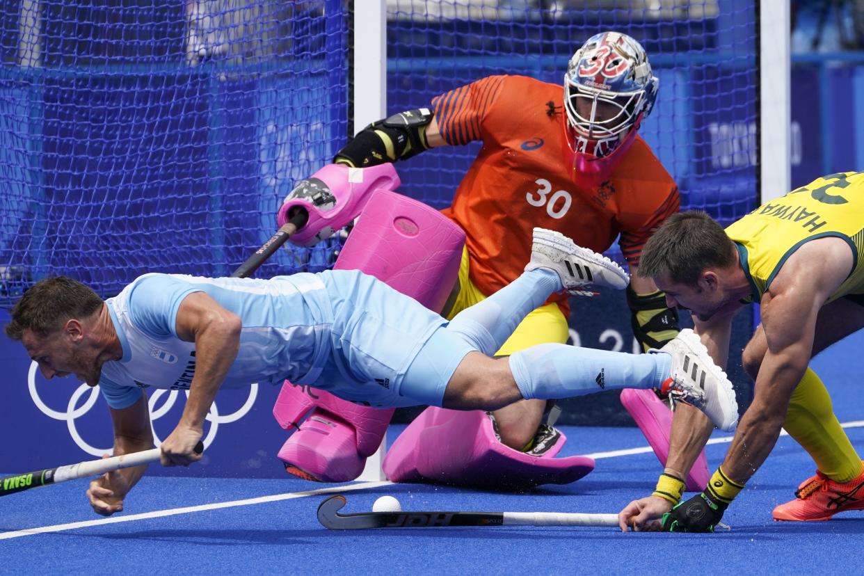 Argentina's Lucas Martin Vila (12) battles with Australia's Jeremy Thomas Hayward (32) on a scoring attempt on goalkeeper Andrew Lewis Charter (30) during a men's field hockey match against Australia at the 2020 Summer Olympics, Tuesday, July 27, 2021, in Tokyo, Japan.