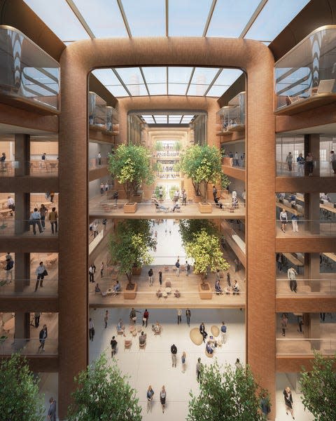 A CGI rendering of the interior of a large office building, with lots of natural light and red brick.