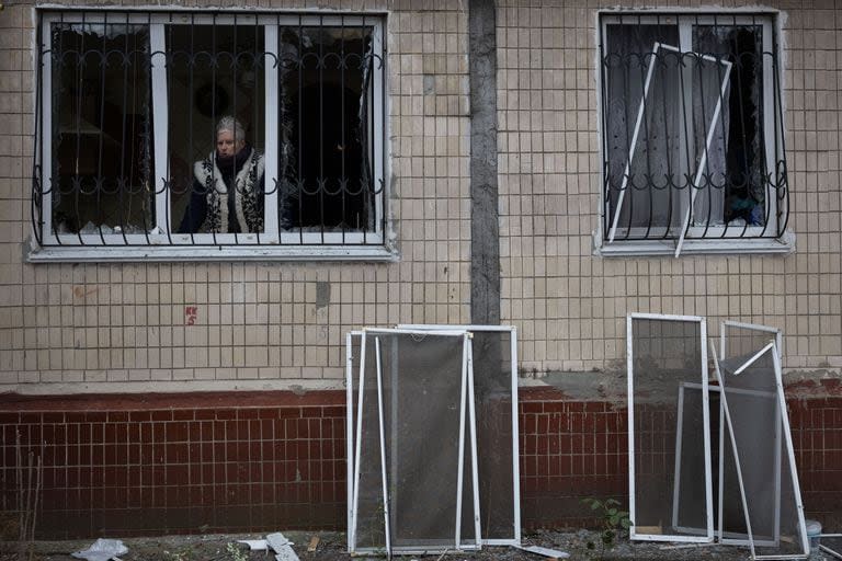 Una residente mira por la ventana de su edificio de apartamentos dañado durante un ataque de misiles rusos en Kiev. 