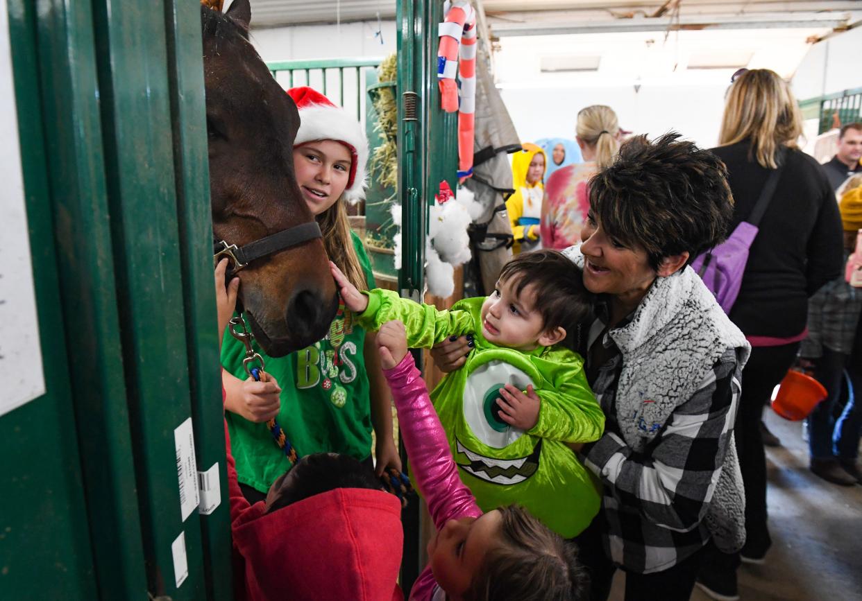 Kathy Luke, right, holds 2-year-old Aiden Hatheway, dressed as Mike Wazowski from Monster's Inc., so he can pet a horse on Saturday, October 30, 2021, during a trick-or-treat event at CK Stables in Harrisburg.