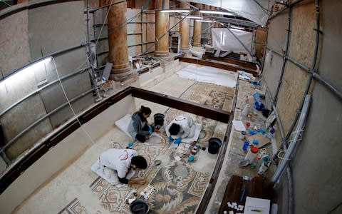 Italian artists at work cleaning and restoring pebble mosaics in the nave - Credit: Thomas Coex/AFP