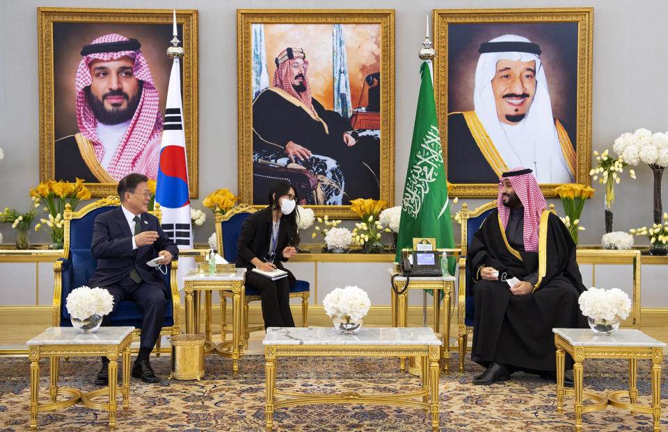 In this photo released by the Saudi Royal Palace, Saudi Crown Prince Mohammed bin Salman, right, meets with South Korean President Moon Jae-in, in Riyadh, Saudi Arabia, Tuesday, Jan. 18, 2022. At top images show Saudi King Salman, right, Saudi Arabia's founding late King Abdul Aziz Al Saud, center and Crown Prince Mohammed bin Salman. (Bandar Aljaloud/Saudi Royal Palace via AP)