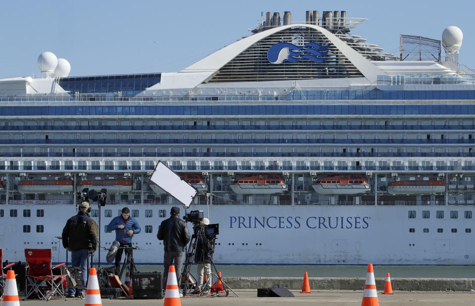 A media crew prepare to film with the Grand Princess cruise ship in the background at the Port of Oakland Thursday, March 12, 2020, in Oakland, Calif. California Gov. Gavin Newsom says nearly 500 passengers remain aboard the cruise ship. In addition to the 21 people who previously tested positive while aboard, Newsom says at least two more people have tested positive after leaving. (AP Photo/Ben Margot)