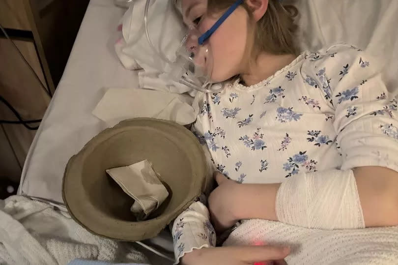 A girl in a hospital bed with an oxygen mask on
