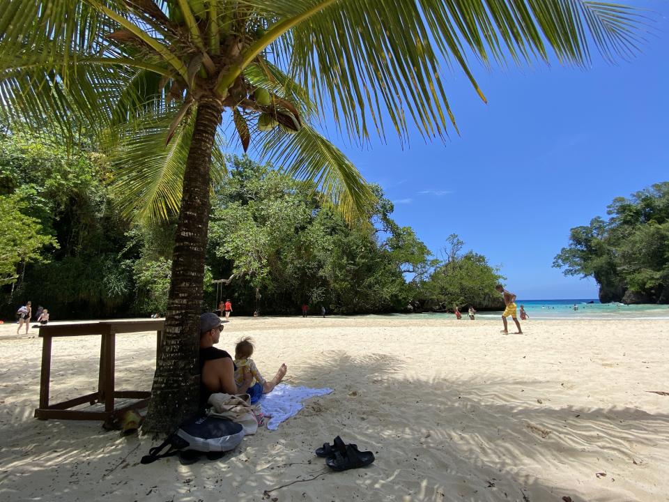 Man sits on beach with a baby