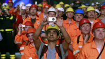 Miners and visitors take pictures as a giant drill machine breaks through the rock at the western tunnel section Sedrun-Faido, at the construction site of the NEAT Gotthard Base Tunnel March 23, 2011. Crossing the Alps, the world's longest train tunnel should become operational at the end of 2016. The project consists of two parallel single track tunnels, each of a lenght of 57 km.