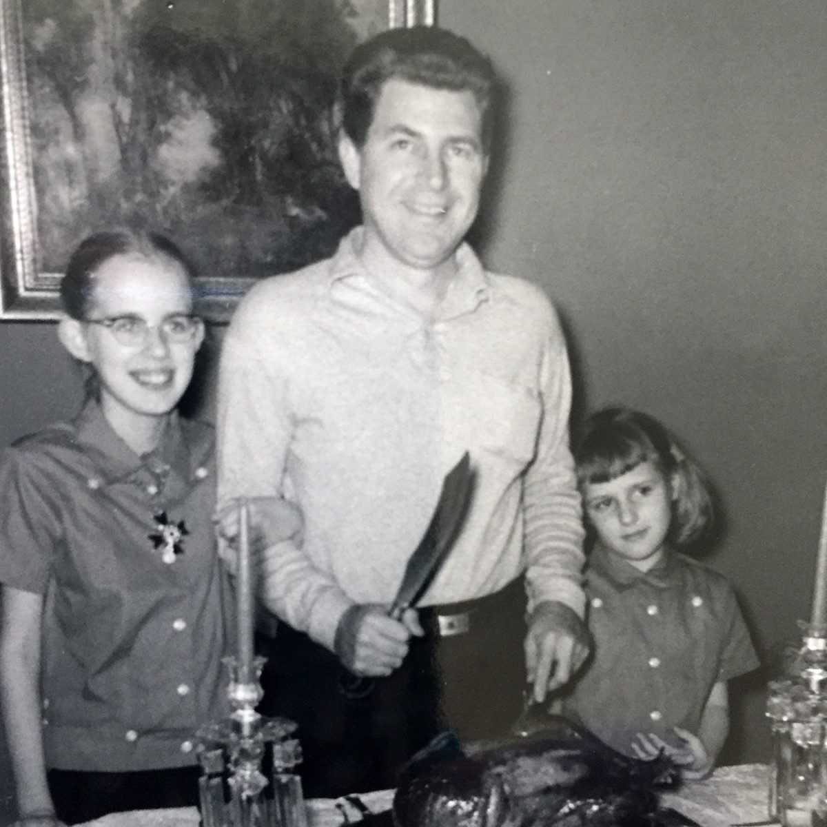 Father and daughters prepare to carve the turkey