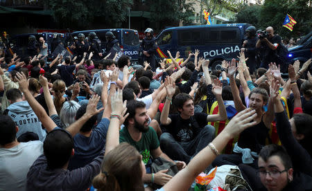 Protestors shout in front of a line of Spanish national police who surrounded the leftist Popular Unity Candidacy (CUP) party headquarters in Barcelona, Spain, September 20, 2017. REUTERS/Albert Gea