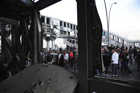 People gather around wreckage after a car bomb at a bus station in Soumariya, near Damascus November 26, 2013, in this handout picture released by Syria's national news agency SANA. REUTERS/SANA/Handout via Reuters
