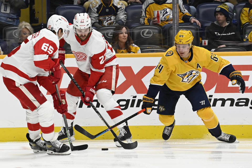 Nashville Predators center Mikael Granlund (64) vies with Detroit Red Wings defenseman Danny DeKeyser (65) and center Michael Rasmussen (27) for the puck during the second period of an NHL hockey game Saturday, Jan. 22, 2022, in Nashville, Tenn. (AP Photo/Mark Zaleski)