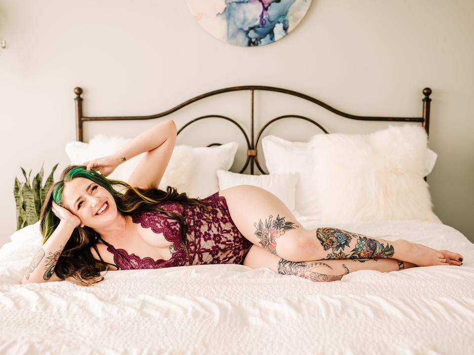 A woman in lingerie poses on a bed for a boudoir photo.