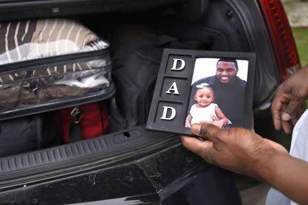 Auto worker Jermaine Austin, who works for General Motors, holds a photograph of him and his two-year-old daughter Jayla before leaving for a new job in Texas, in Kansas City, Missouri May 16, 2015. REUTERS/Ed Zurga